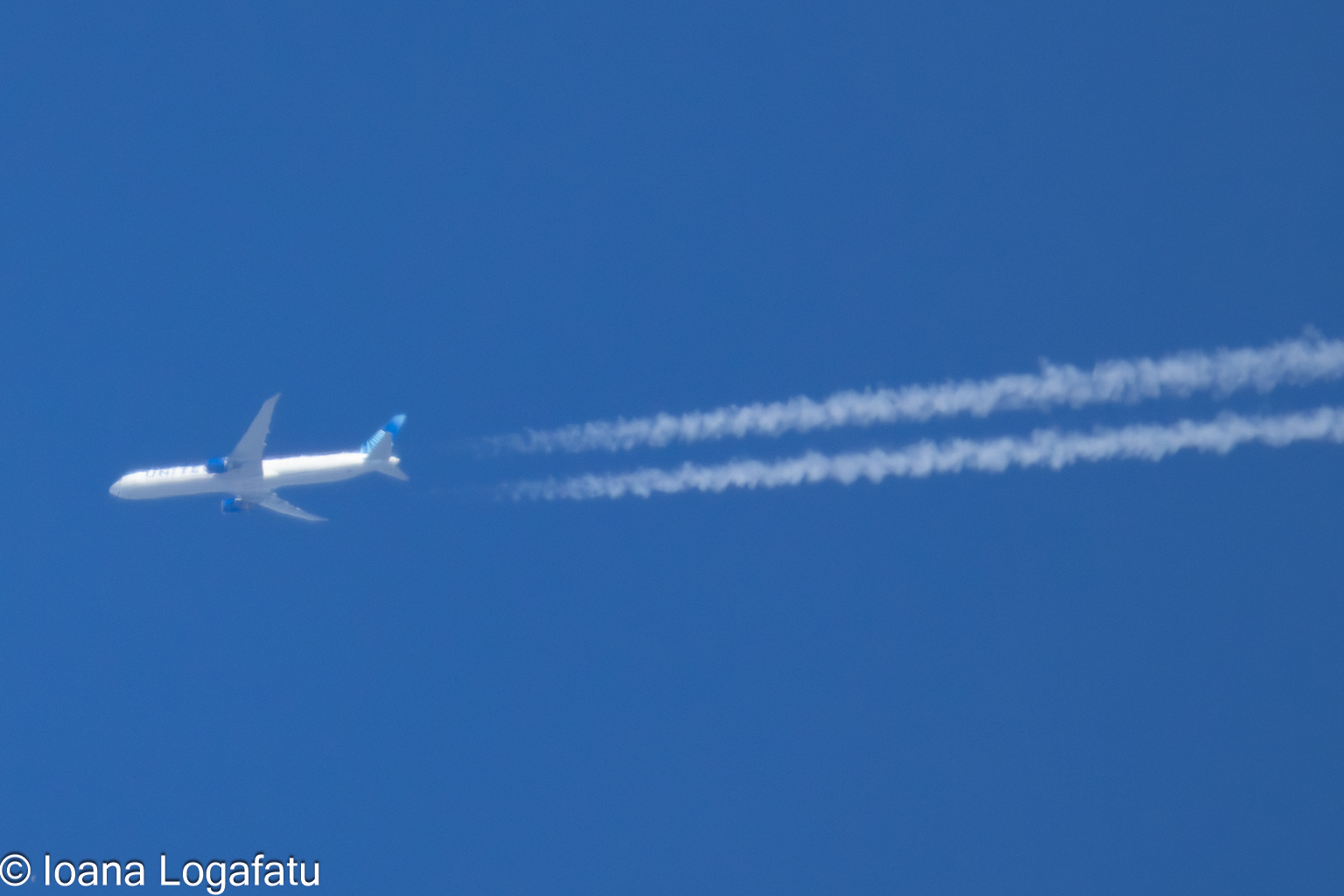 High above, an airplane glides through clear skies